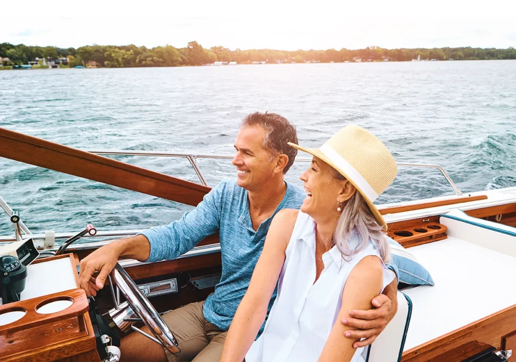 Older man and woman, mature couple, laughing and smiling, while drive their boat around the lake.